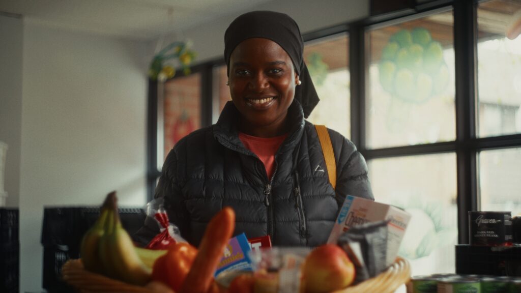 BYOA program participants Community member smiling and holding a food hamper at The Stop's Food Bank